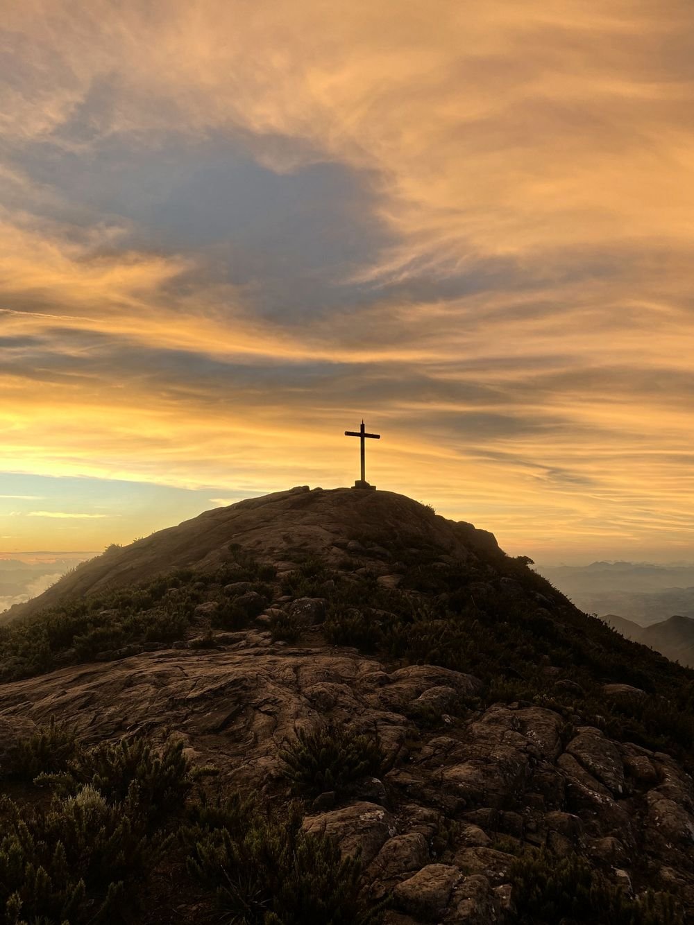 O cruzeiro no alto do cume sob o céu dourado do fim de tarde