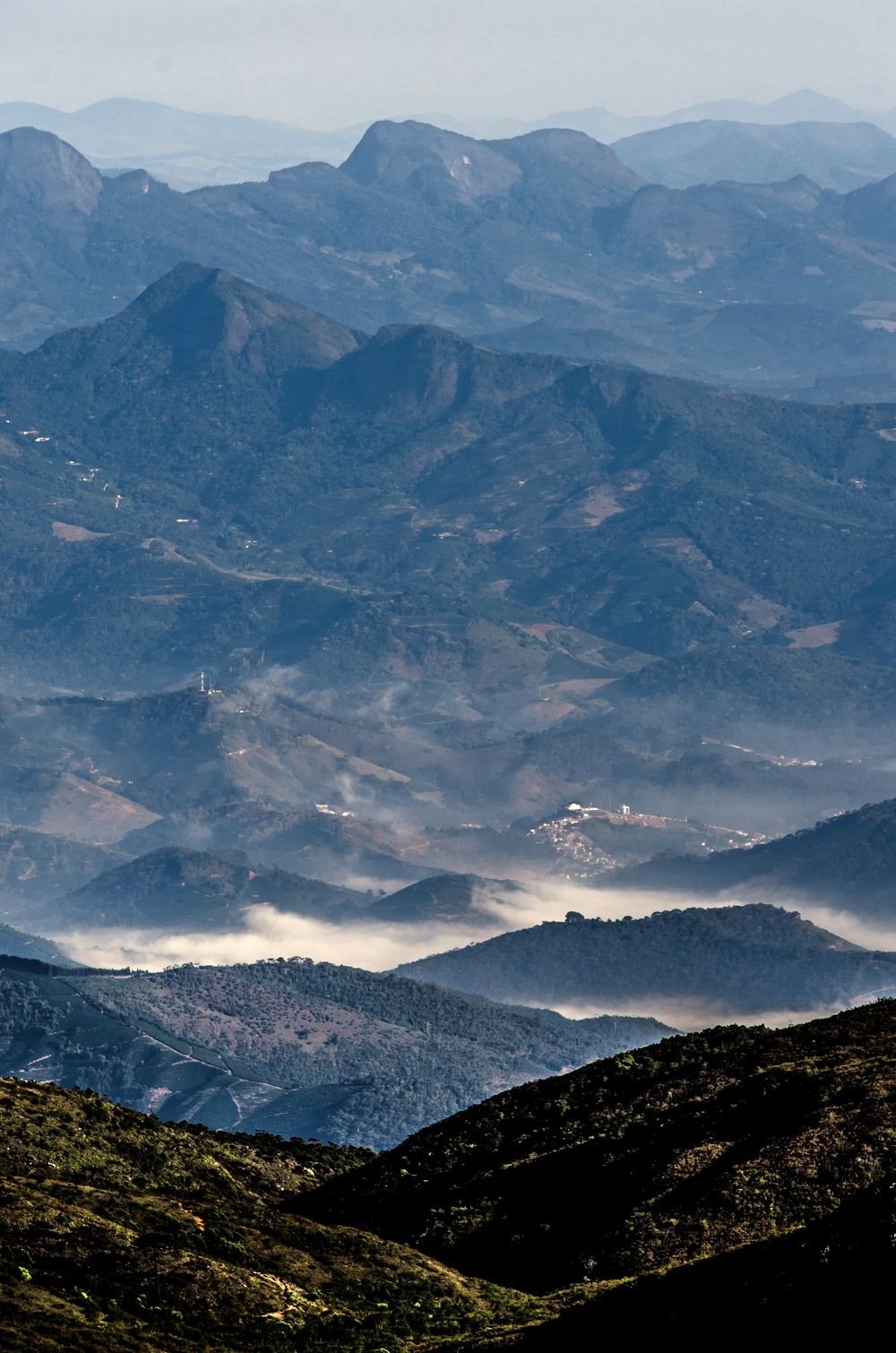 Camadas de montanhas azuladas com névoa nos vales, vistas do alto
