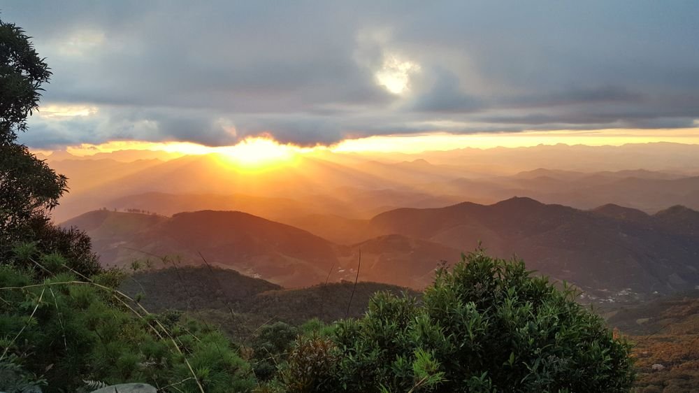 O sol rompendo as nuvens sobre as montanhas, visto do Mirante do José Pedro