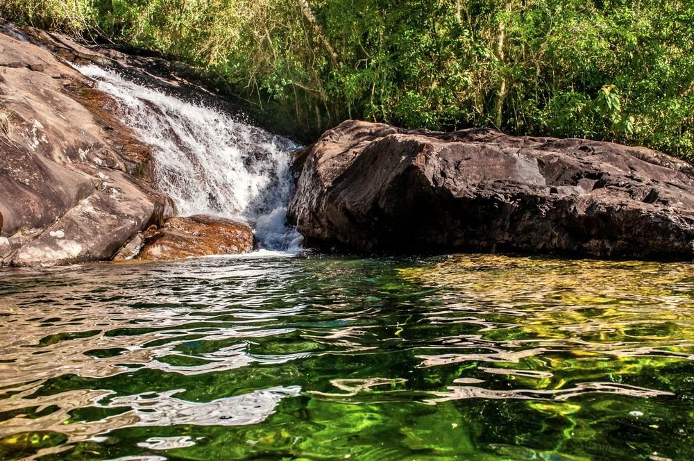 Uma queda d'água sobre a rocha e o poço de água verde da cachoeira do Vale Verde
