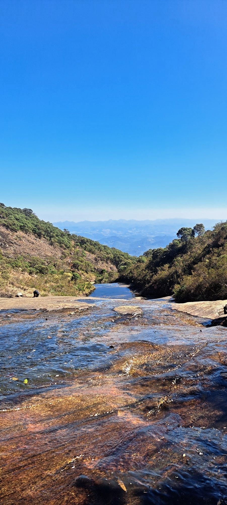 Pessoa se banhando num poço de água cristalina entre as pedras