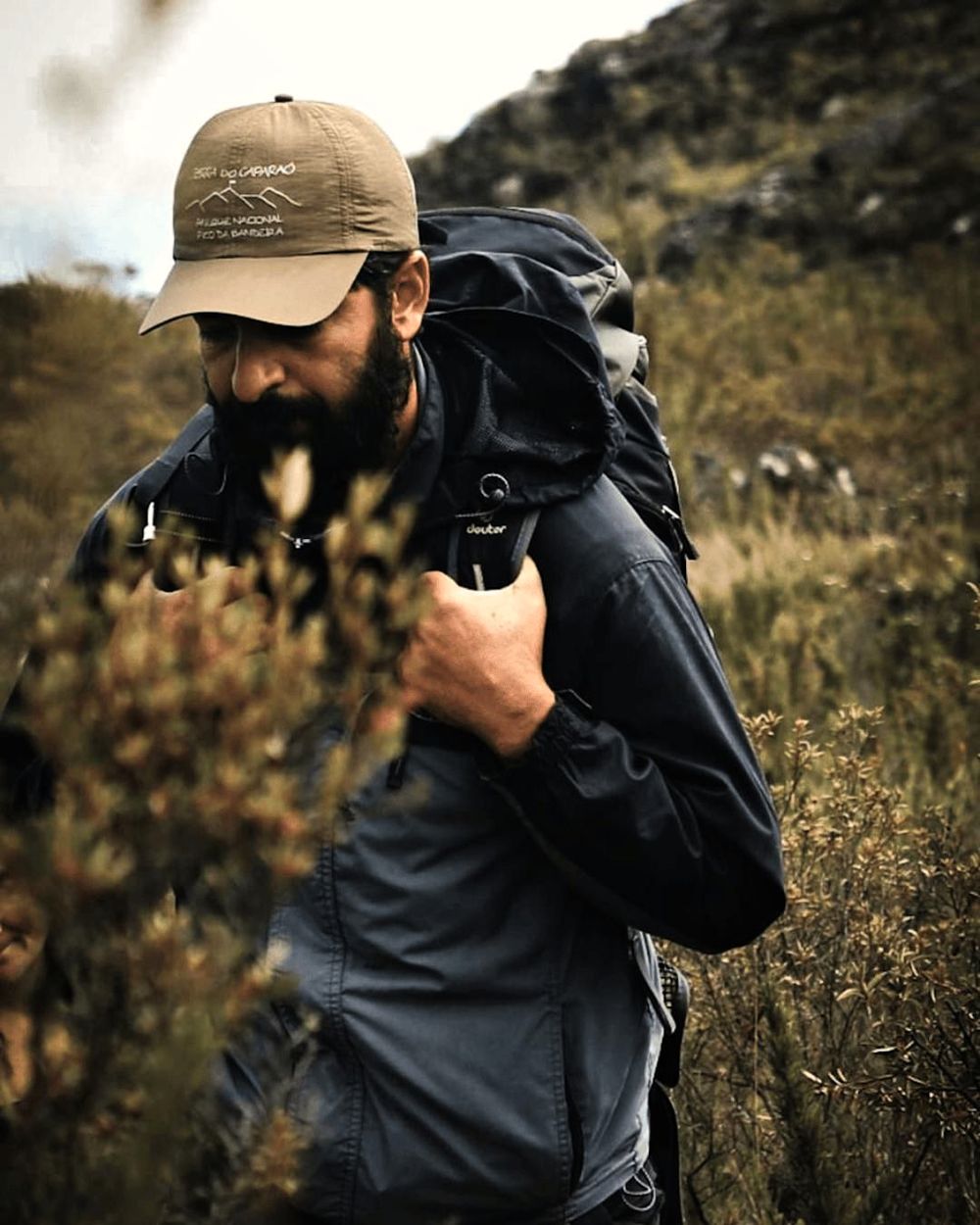 Sairo Guedes na trilha, com mochila cargueira e o boné do Parque Nacional do Caparaó