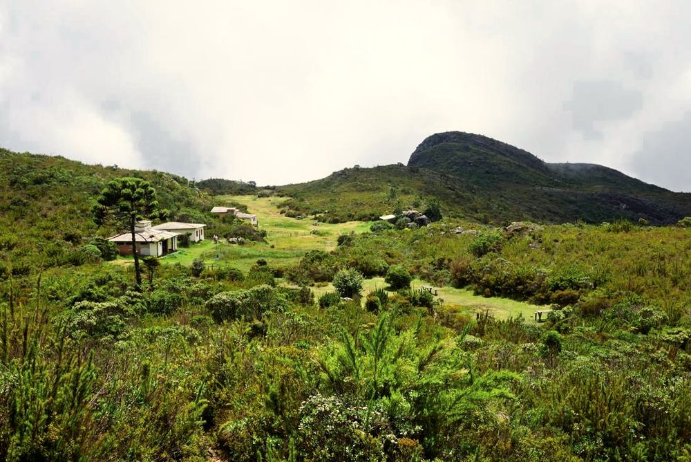 Construções do acampamento do Terreirão em meio ao campo de altitude, com a serra ao fundo